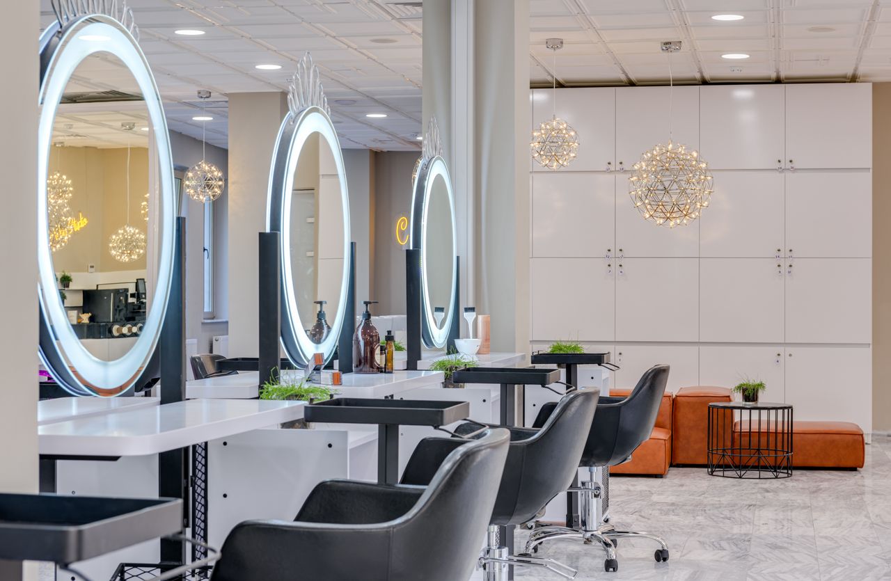 Services-02 Bright and elegant hair salon interior featuring modern lighting and round mirrors for a chic and relaxing atmosphere.